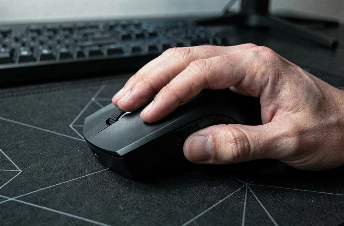 Gros plan sur une main de gamer tenant une souris gaming sur tapis de souris, illustrant la précision et les réflexes lors d'un test de performance